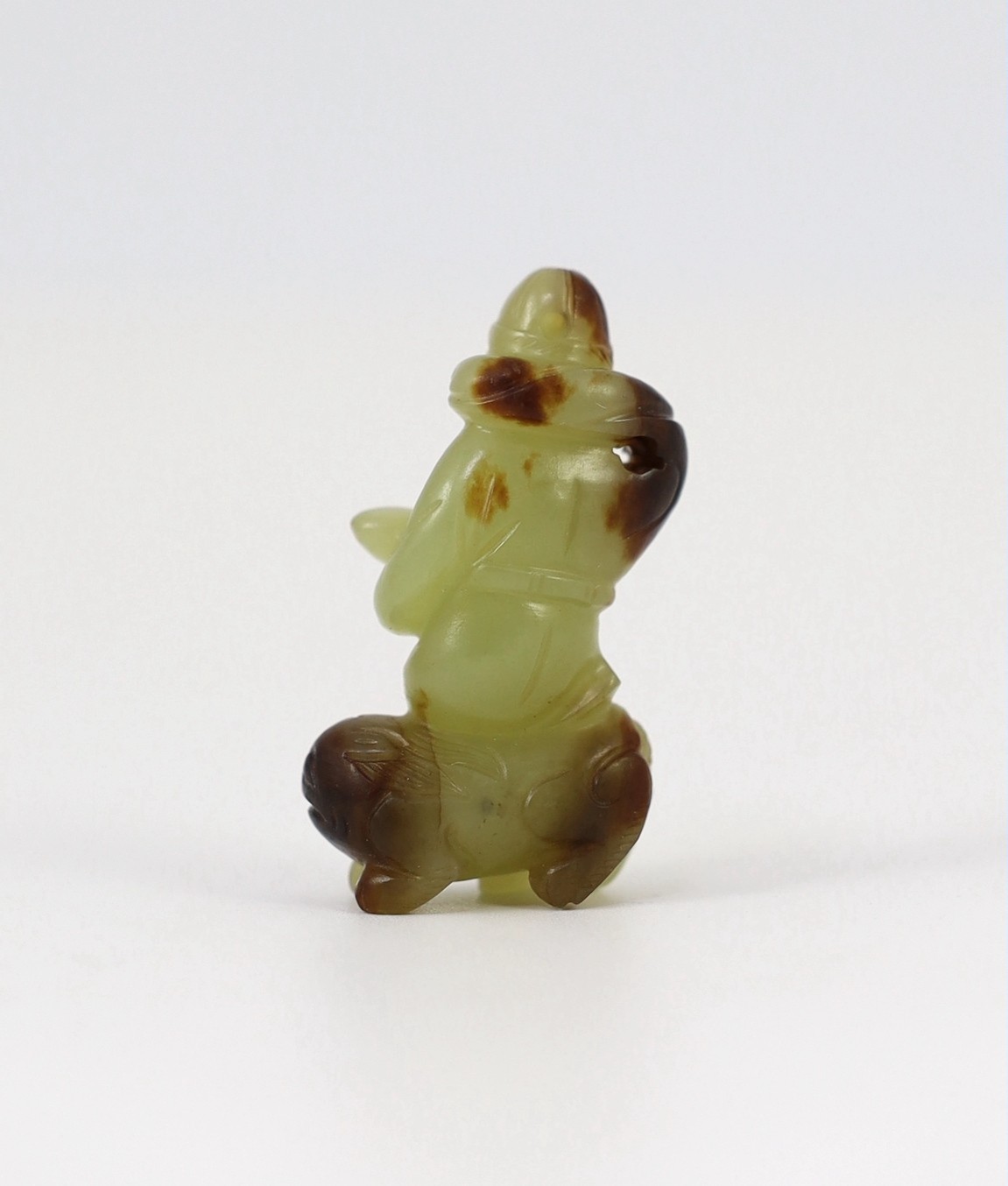 A Chinese yellow and brown jade figure of a man seated on a creature, 19th century, 4.3cm high